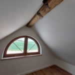 małe półokrągłe okno na strychu po remoncie przez firmę budowlaną MM Bujak