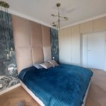 duże łóżko z niebieską pościelą z telewizorem na ścianie w sypialni wykończonej przez firmę budowlaną MM Bujak