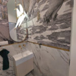 lustro o owalnym kształcie nad umywalką w łazience o ścianach ozdobionych malowidłami ptaków