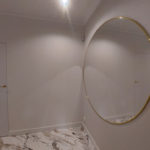 duże okrągłe lustro ze złotym obramowaniem na ścianie w pokoju po remoncie przez firmę budowlaną MM Bujak
